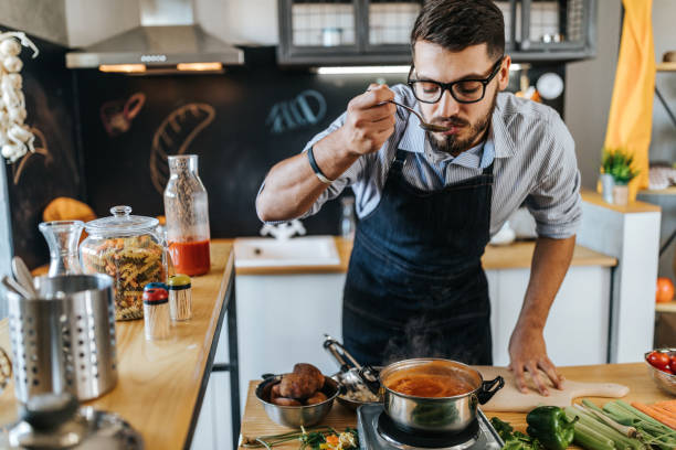 This smells so delicious Photo of chef tasting delicious lunch he is preparing in the kitchen tasting stock pictures, royalty-free photos & images
