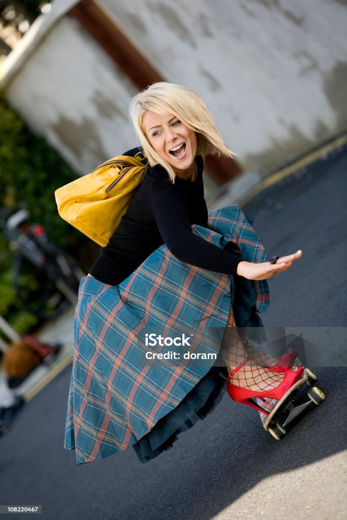 Giovane donna che indossa tacchi alti e montare Skateboard - Foto stock royalty-free di Bizzarro