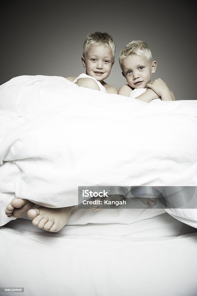 Dos hermanos rubia sentada en la cama - Foto de stock de 6-7 años libre de derechos