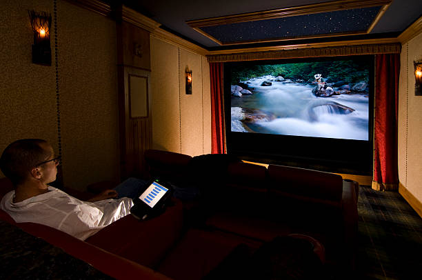 Home Theater A man sits in is home theater watching a movie with copy-space. entertainment center stock pictures, royalty-free photos & images