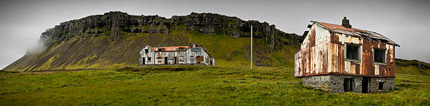 A farm sits quietly at the foot of mountains in Iceland