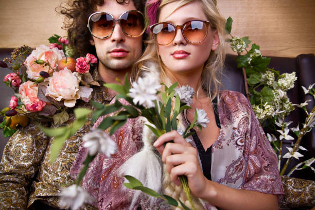 Young Hippie Man and Woman Holding Flowers  hippie fashion stock pictures, royalty-free photos & images
