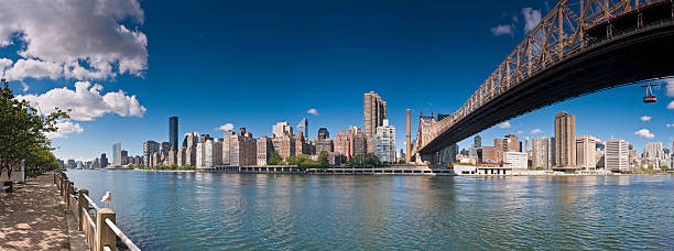 New York from Roosevelt Island View across the East River from the UN Headquarters, past the skyscrapers of Midtown, the apartment blocks of the Upper East Side and Sutton under the Queensboro Bridge to Yorkville and beyond in this panoramic vista of Manhattan, New York. ProPhoto RGB profile for maximum color fidelity and gamut. roosevelt island stock pictures, royalty-free photos & images