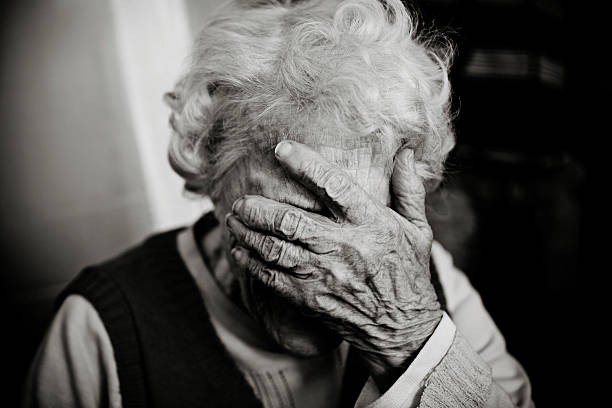 Senior Woman Holding Head in Hand, Black and White stock photo