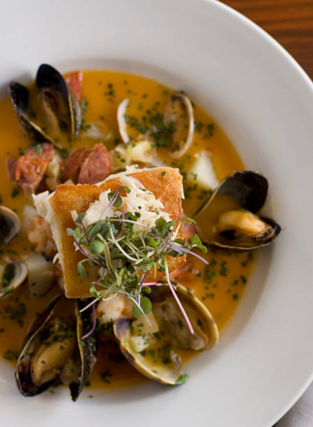 Hearty seafood soup with mussels, clams and a grilled filet of sea bass in a saffron curry broth.  Sea bass is topped with cooked crabmeat and the whole dish is sprinkled with chopped parsley.