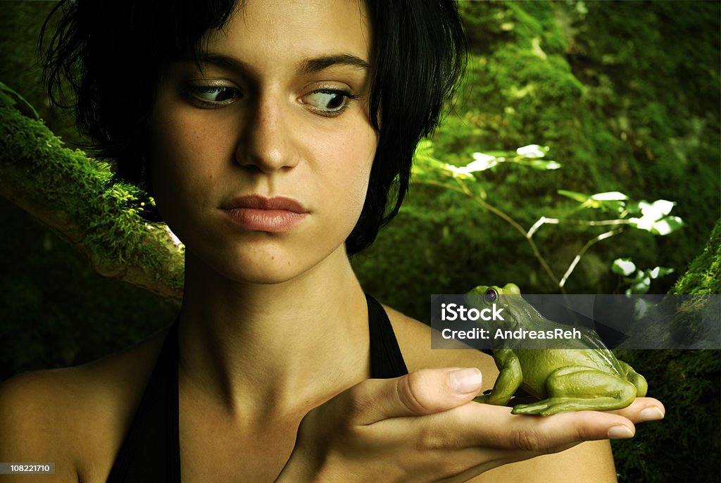 Молодая женщина, удерживая глядя на лягушка - Стоковые фото Сказка роялти-фри