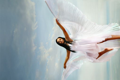 Beautiful girl levitating in mid-air, falling down and her hair messed up soaring from wind, model flying hovering with dreamy peaceful expression in sky. collage composition on day cloudy blue sky