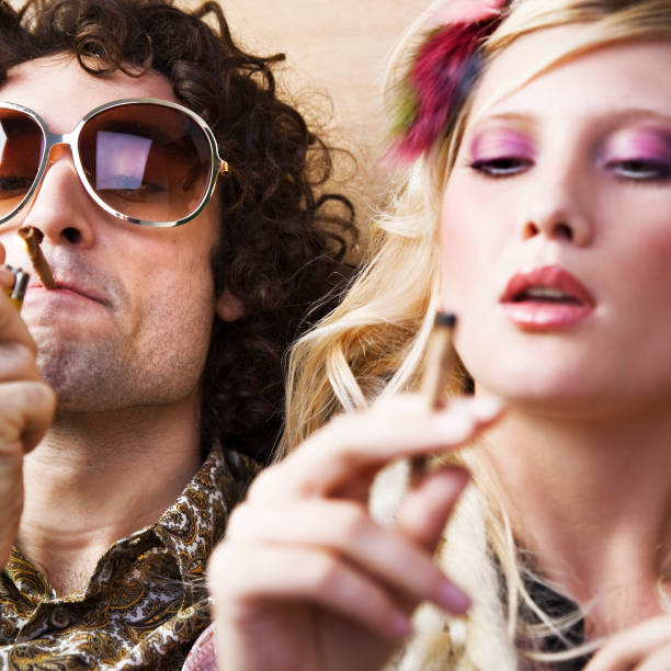 若い hippie の男性と女性の喫煙マリファナ - 1970s style hippie couple retro revival ストックフォトと画像