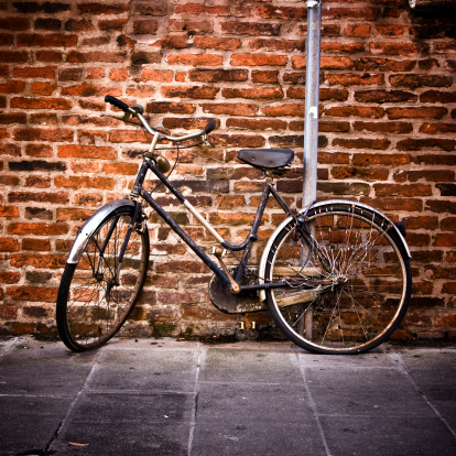 Bicycles are parked in a special parking lot near the large wall of the castle made of old red brick in the old streets of Europe in the center of Krakow