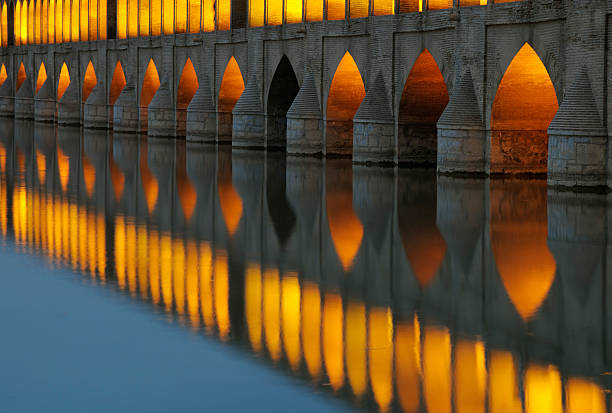 Isfahan, Iran - April 24, 2017: The ancient stone pedestrian Khaju bridge with arches crosses the river Zayandeh in the light of the setting sun.