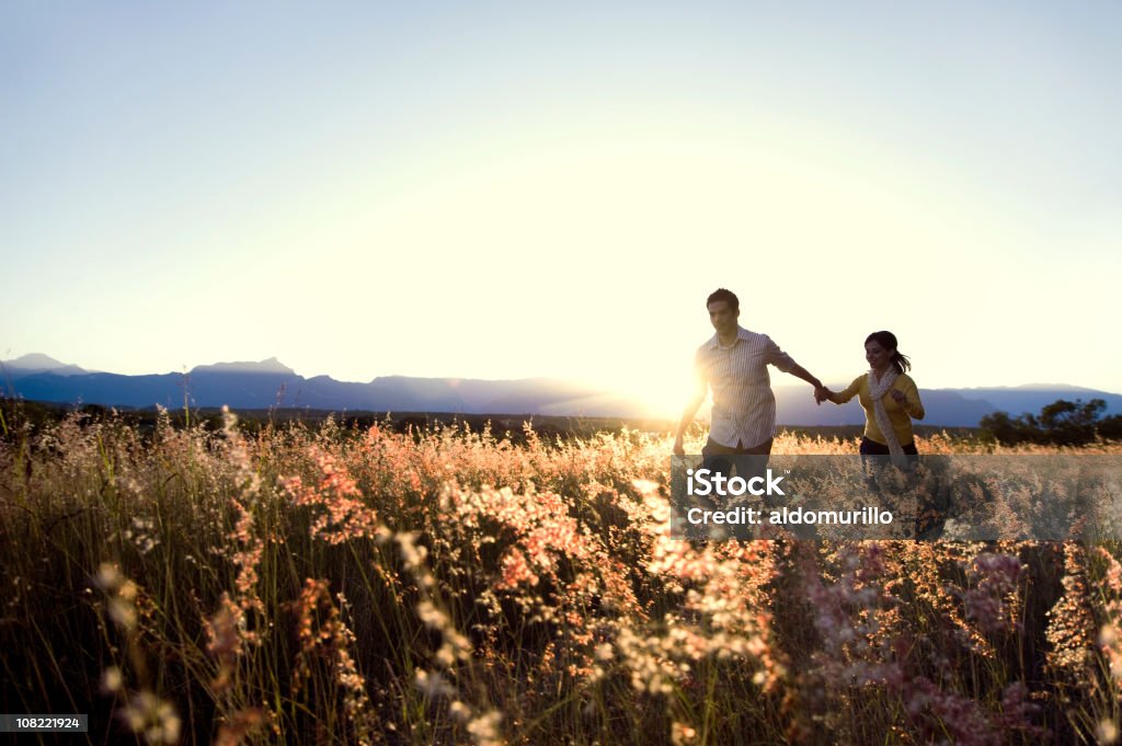 Casal caminhar através de alto grama campo ao pôr do sol - Royalty-free Andar Foto de stock