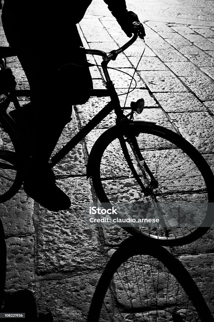 Sagoma della persona Bicyling sulla strada di ciottoli. Bianco e nero - Foto stock royalty-free di Città