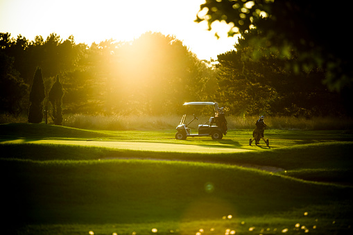 Golf cart on the course at sunset. No people and room for copy space.
