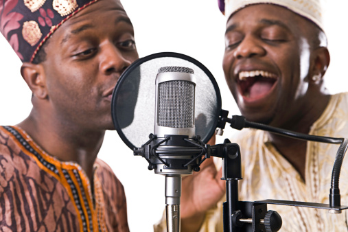 Two ethnic musicians representing their cultural heritage in the recording studio with traditional clothing; isolated on a white studio background.