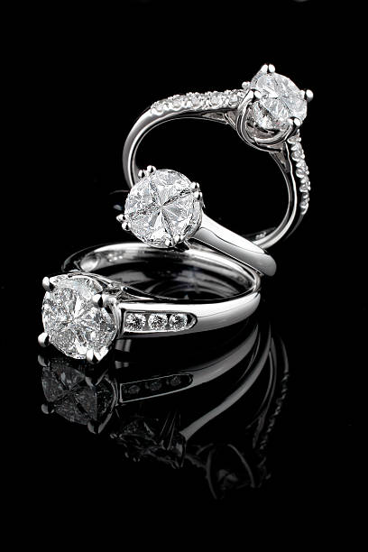 tres diamantes blanco anillos de oro sobre fondo negro - anillo joya fotografías e imágenes de stock