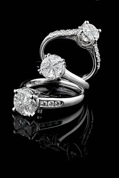Photo of Three white gold diamond rings on black background