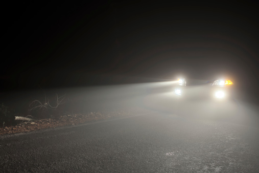 Headlights of a car driving in the fog at night