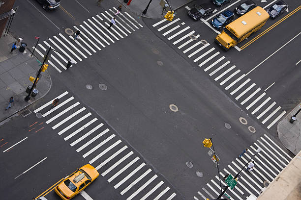 Manhattan, New York City, New York United States - August 25 2021: Street intersection with crosswalks, pedestrians, traffic, and taxi cab. View from above.