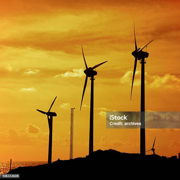 Silhuetas De Turbinas De Vento Na Colina Ao Pôr Do Sol - Fotografias de stock e mais imagens de Amarelo