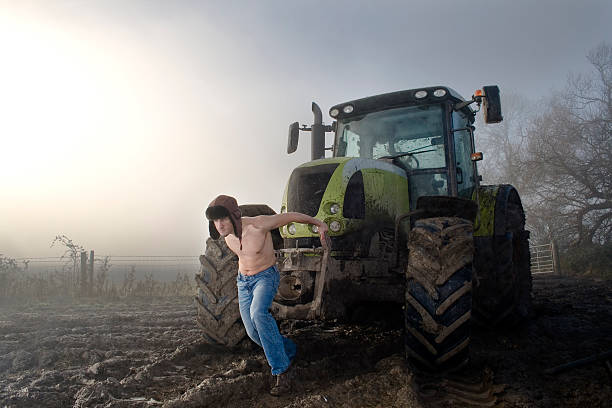 Shirtless Young Man Pulling Tractor on Foggy Field stock photo