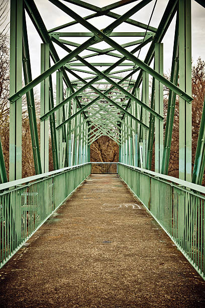 Concrete pedestrian bridge in a public health park surrounded by greenery and walking paths.