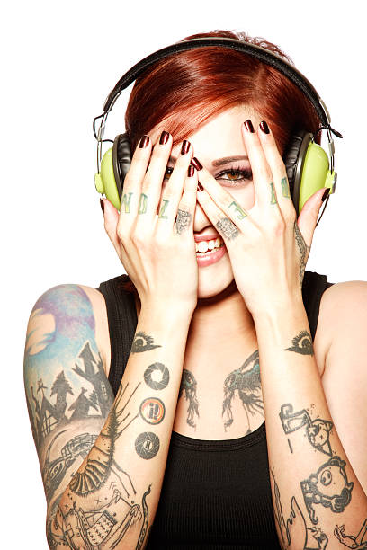 молодая женщина носить наушники и закрывать лицо с руки - headphones women tattoo music стоковые фото и изображения