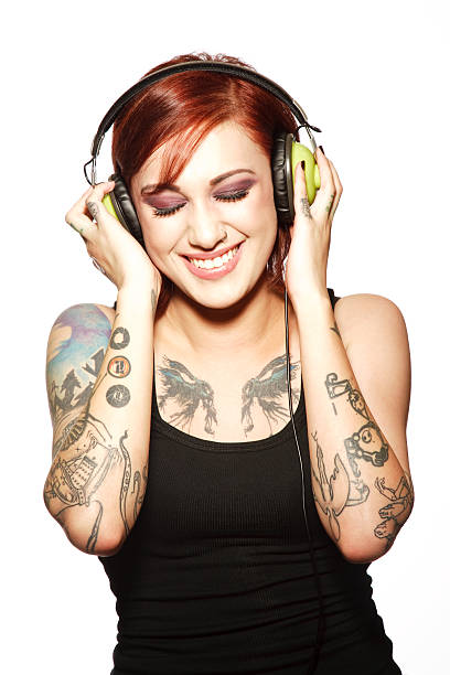 портрет улыбающегося молодой женщины с татуировками слушая наушники - front view female isolated on red happiness стоковые фото и изображения