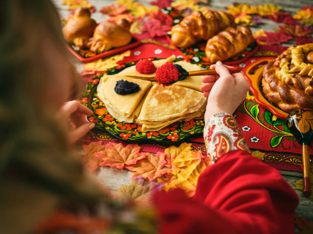 Russian Traditional Blini and Caviar on a Table A woman putting caviar on a blini on a traditional Russian table. russian ethnicity stock pictures, royalty-free photos & images