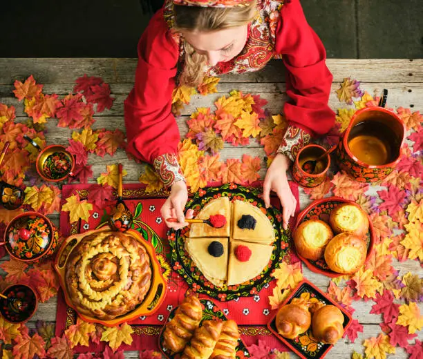 A top down view of traditional Russian holiday breads on a table including blini, karavai pancakes.