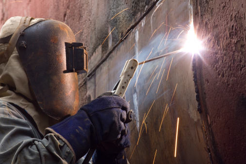 Welding new steel plates on a ship's hull during repair work on a ship in a dry dock.