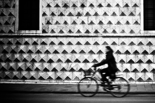 Cycling outdoors in a footpath with arched walls arcade roof covered with sorghum stalks, sunny day with shadows. Surface level view with grayscale colors contrasted.