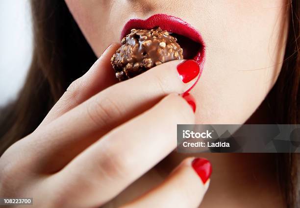 Closeup Of Young Womans Mouth Comiendo Chocolate Foto de stock y más banco de imágenes de 20-24 años - 20-24 años, Adulto, Adulto joven