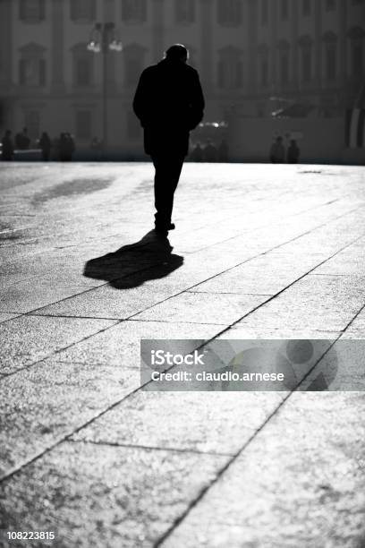 Silhouette Di Uomo Che Cammina Attraverso Piazza Cittadina Bianco E Nero - Fotografie stock e altre immagini di Uomini
