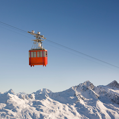 New modern spacious big cabin ski lift gondola against snowcapped forest tree and mountain peaks covered in snow landscape in luxury winter alpine resort. Winter leisure sports, recreation and travel.