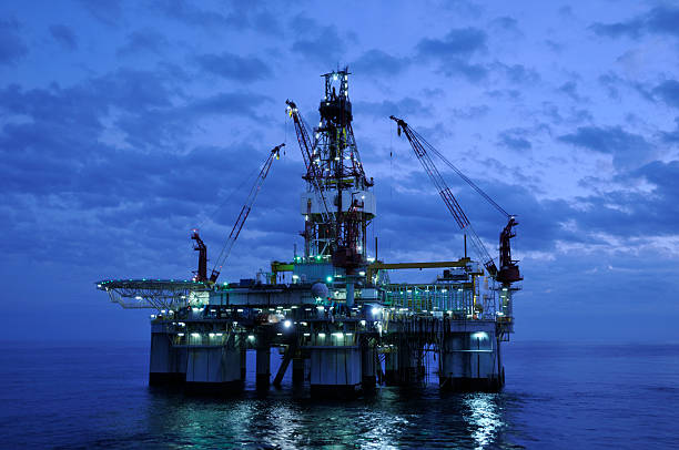 de terra plataforma de perfuração no crepúsculo. plataforma petrolífera e reflexo - oil rig sea oil well oil drill - fotografias e filmes do acervo