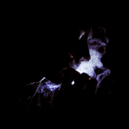 man smoking in the dark, illuminated by a torch LED light