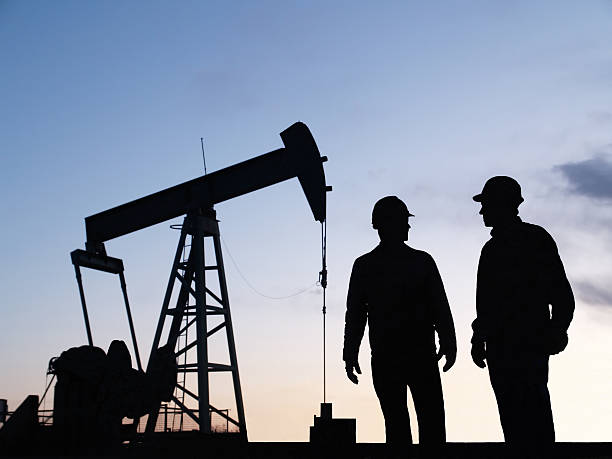 Bomba de óleo Pumpjack & trabalhador silhuetas - foto de acervo