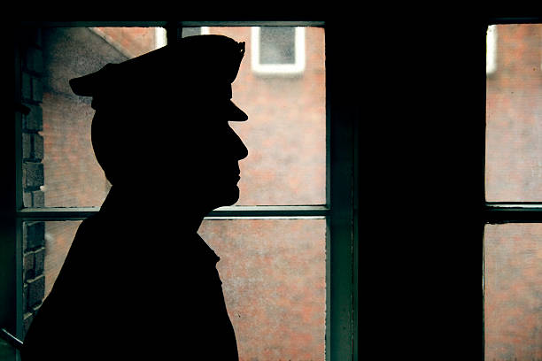 Silhouette of a prison/police warden Warder's silhouette, prison walls outside the window. prison guard stock pictures, royalty-free photos & images