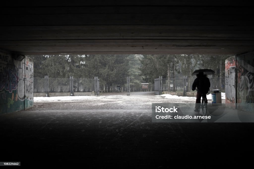 Persona sotto il ponte bicicletta di equitazione durante l'inverno - Foto stock royalty-free di Bicicletta