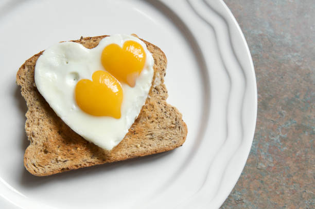 coração forma saudável comer ovos de café-da-manhã na torrada - eggs breakfast heart shape fried egg - fotografias e filmes do acervo