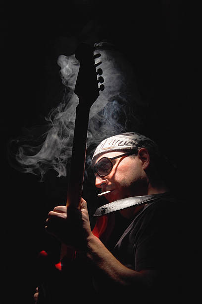 Hombre tocando la guitarra y fumar cigarrillos, bajo llave - foto de stock