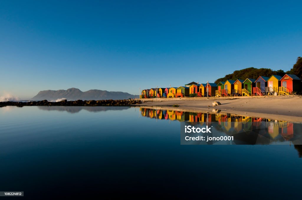 Colorful houses seaside landscape St James beach , Cape Town.  Colorful bathing huts reflecting in tidal pool at sunrise Cape Town Stock Photo