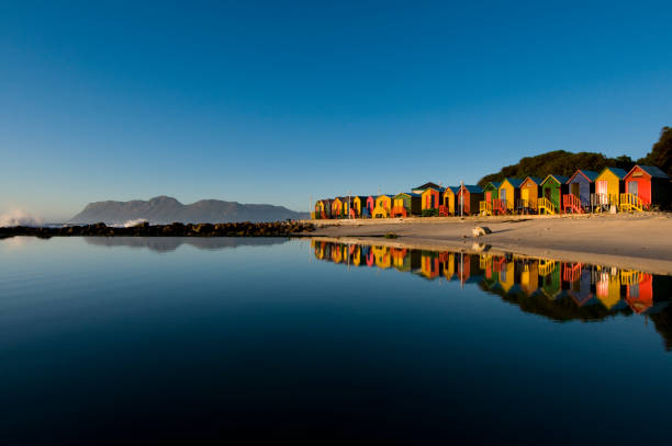 Colorful houses seaside landscape St James beach , Cape Town. Colorful bathing huts reflecting in tidal pool at sunrise pretty beach house stock pictures, royalty-free photos & images