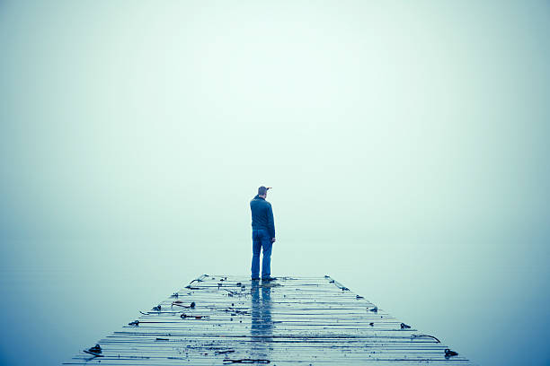 uomo guarda attraverso la nebbia e in piedi sul dock - segnale di strada senza uscita foto e immagini stock