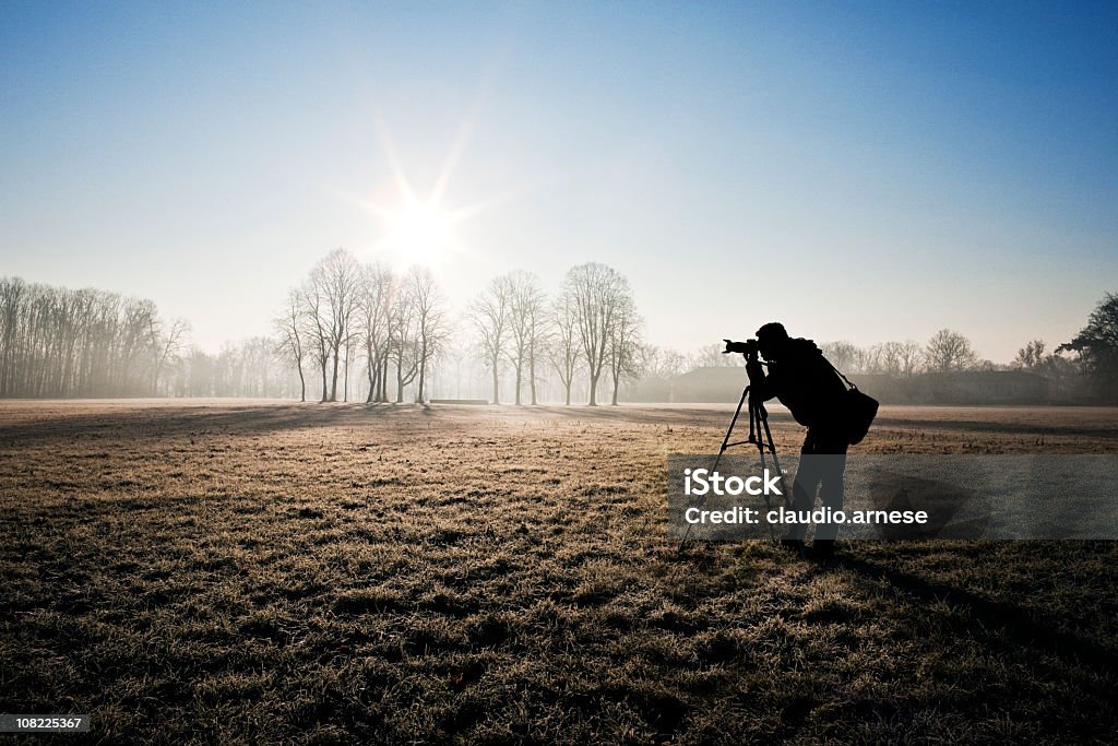 Sylwetka fotografa w polu. Słoneczny dzień. Obraz w kolorze - Zbiór zdjęć royalty-free (Aparat fotograficzny)