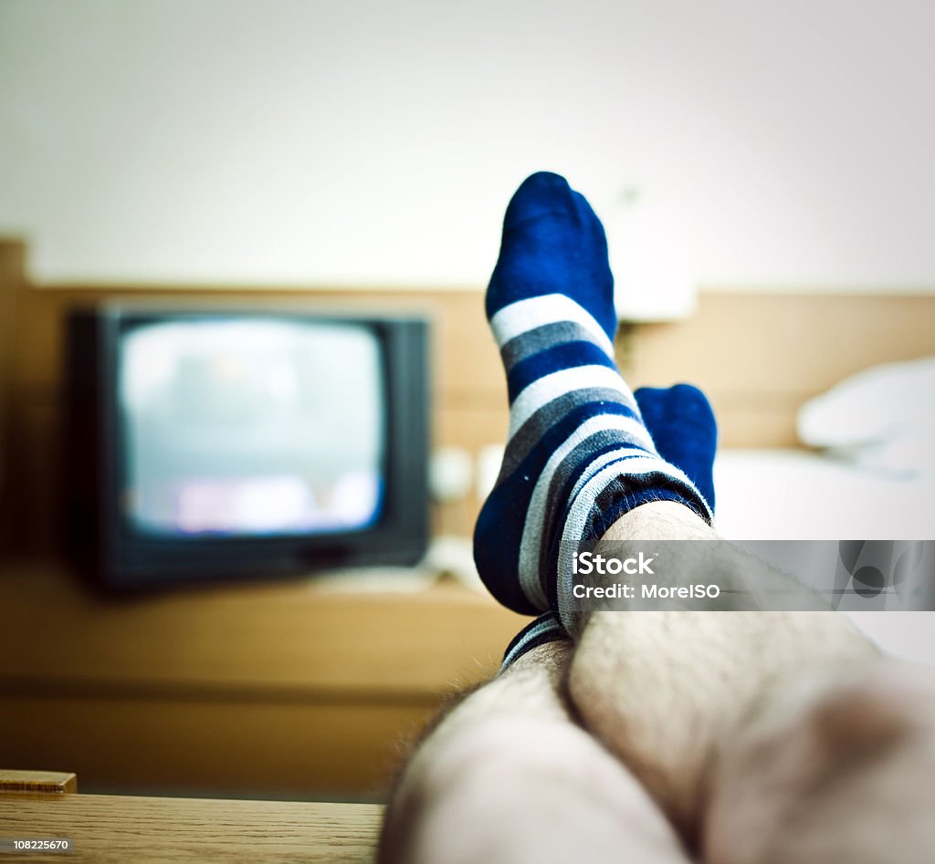 Homme de jambes vous détendre devant la télévision - Photo de Chaussette libre de droits