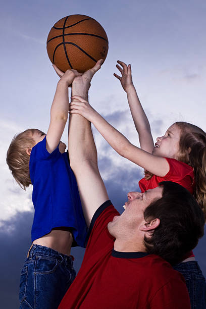 Father, son and daughter playing basketball stock photo