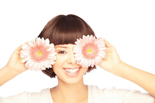 Portrait of a happy young woman covering her one eye with a flower