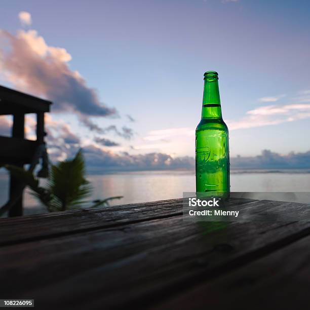 Foto de Cerveja Ao Pôrdosol e mais fotos de stock de Garrafa de Cerveja - Garrafa de Cerveja, Cerveja, Verde - Descrição de Cor