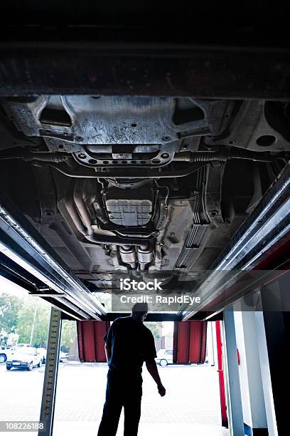 Debajo De Un Coche Foto de stock y más banco de imágenes de Mecánico - Mecánico, Silueta, Coche